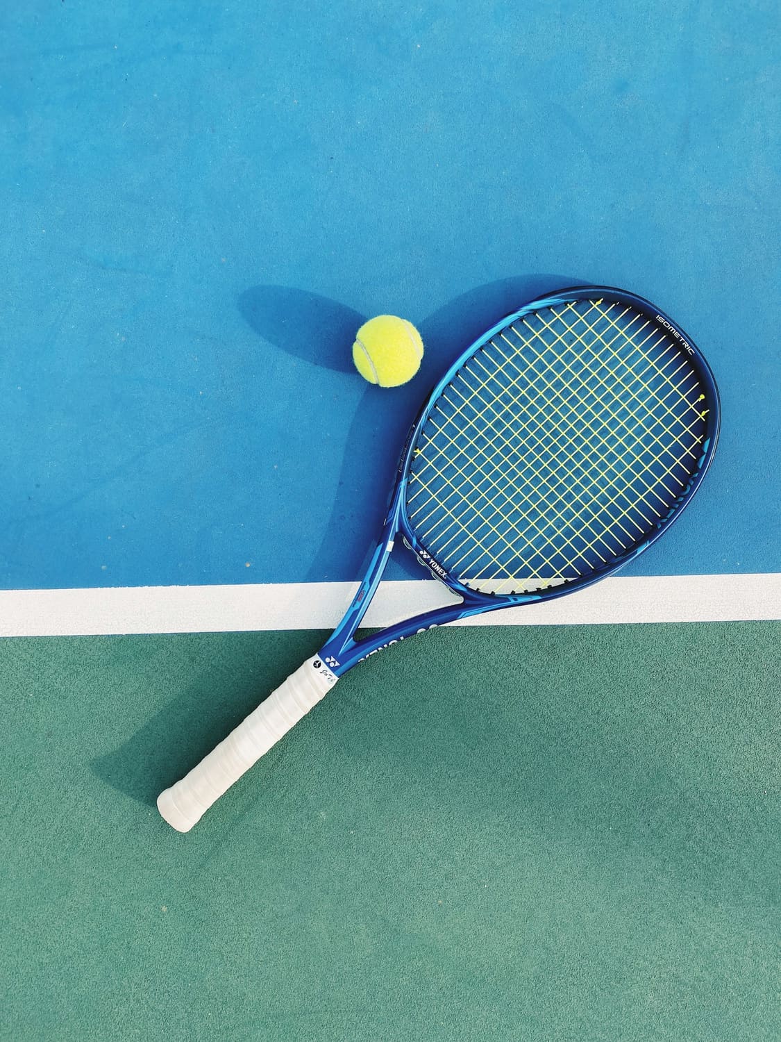 Blue and white tennis racket with a ball on a court