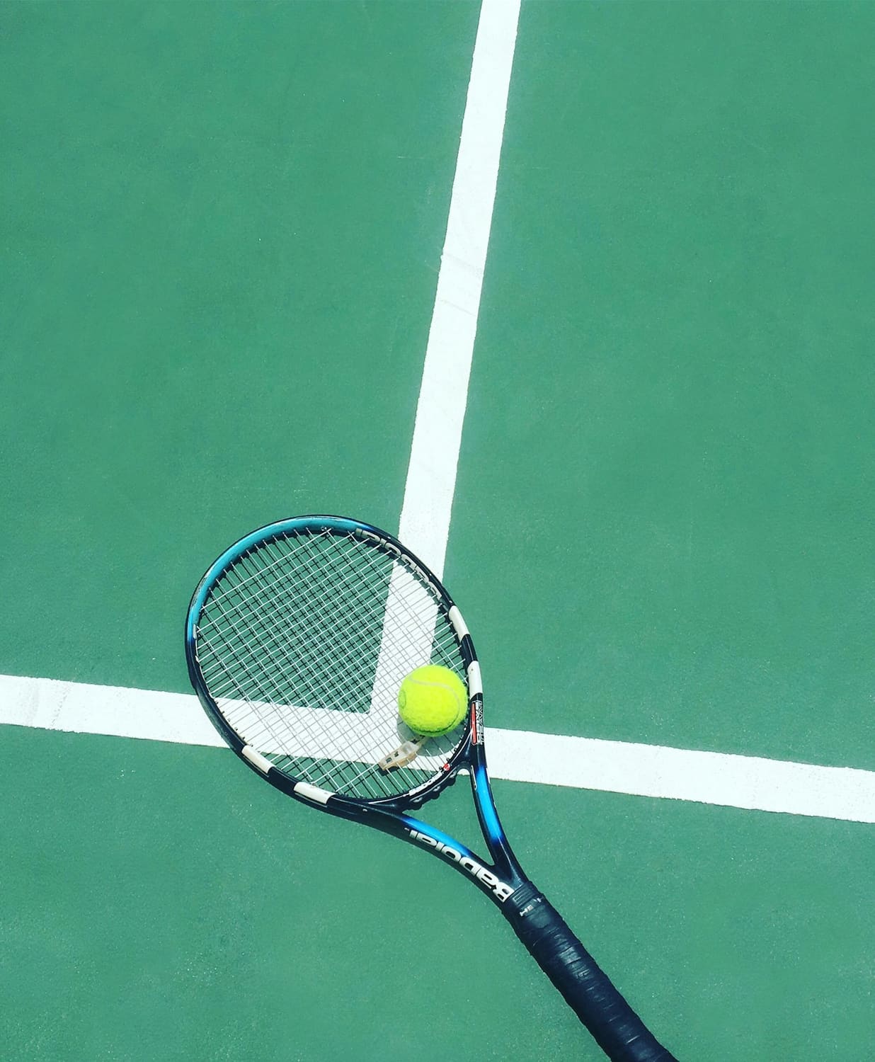 Tennis racket and ball on a green court